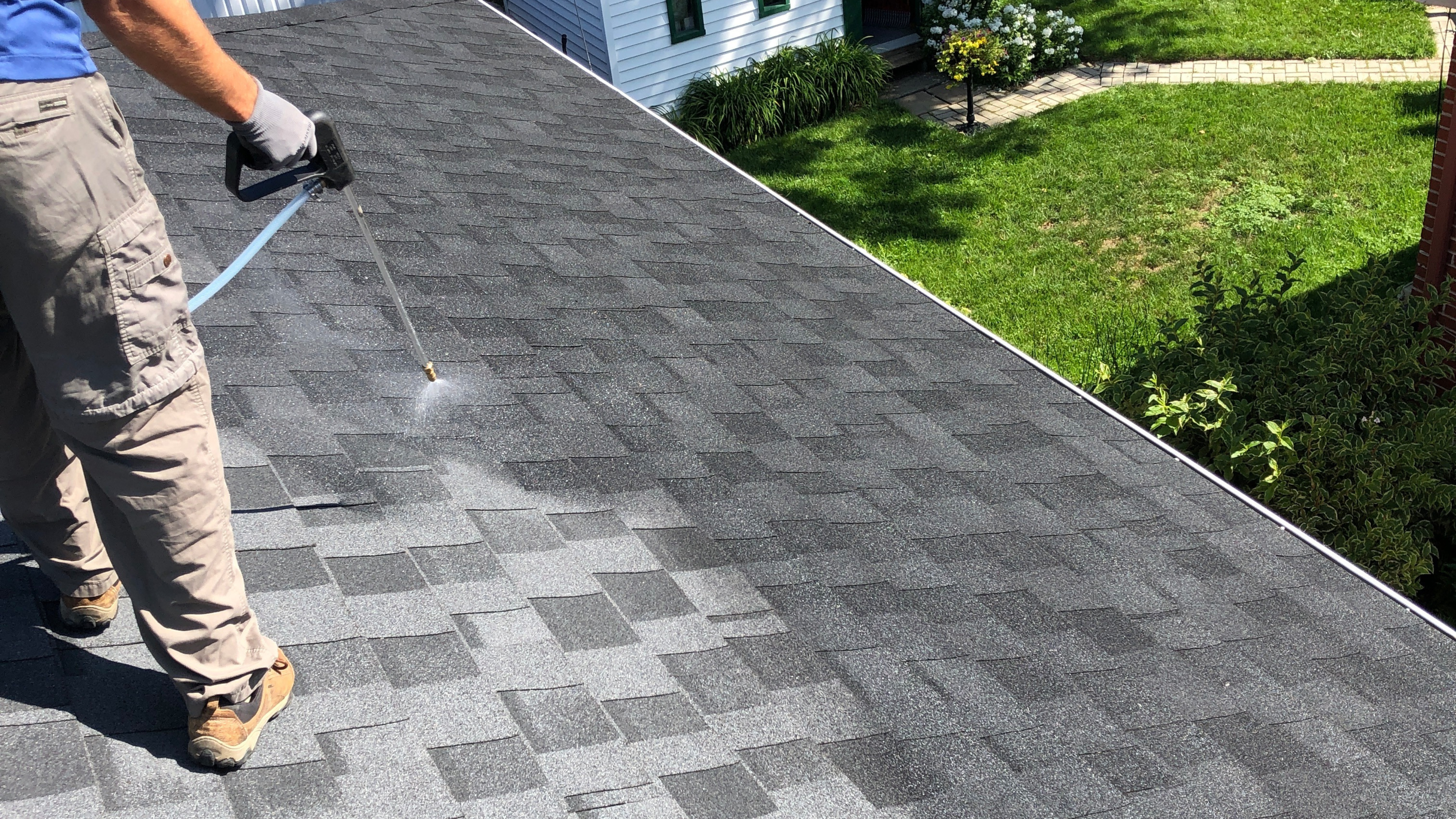 Technician applying GoNano roof rejuvenation treatment to asphalt shingles, similar to work done in the Roanoke area